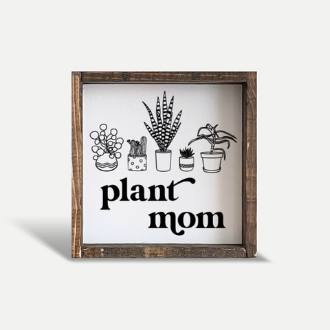 Decorative sign with plant illustrations and 'plant mom' text on a white background
