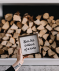 Stack of firewood in a fireplace with a framed sign held in front
