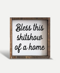 Wooden sign with text 'Bless this shitshow of a home' on a white background
