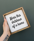 Hand holding a framed sign with text against a dark background