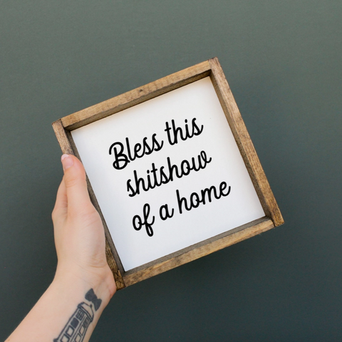 Hand holding a framed sign with text against a dark background