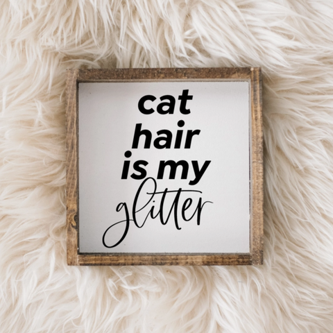 Framed sign with 'cat hair is my glitter' text on a fluffy white surface