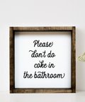 Framed sign with text 'Please don't do coke in the bathroom' on a white wall with a vase and plant.