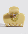 Decorative beige hair clip with a bird and floral design on a light gray background