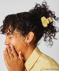 Woman with styled hair wearing a yellow bow and shirt against a light gray background