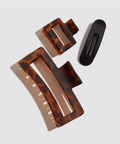 Two tortoiseshell hair clips and a black clip on a light gray background