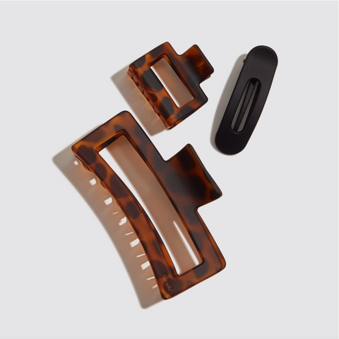 Two tortoiseshell hair clips and a black clip on a light gray background