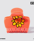 Orange hair clip with a cartoon flower design on a white background, featuring the BT21 brand.