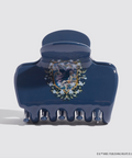 Blue hair clip with a decorative emblem on a light gray background