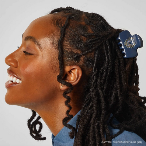 Person with braided hair wearing a blue shirt against a white background