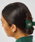Person with a green hair clip in their hair against a gray background