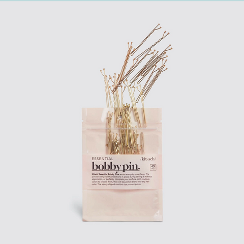 Set of bobby pins in a clear plastic bag with a beige label on a light blue background