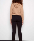 Person wearing a beige hoodie and black pants against a white background