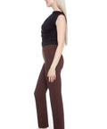 Person wearing a black sleeveless top and brown pants on a white background