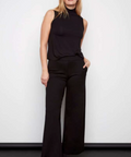 Woman wearing a black sleeveless top and wide-leg pants against a white background