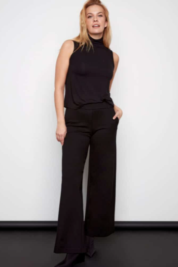 Woman wearing a black sleeveless top and wide-leg pants against a white background