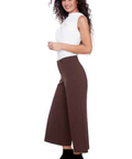 Woman wearing a white top and brown wide-leg pants on a white background