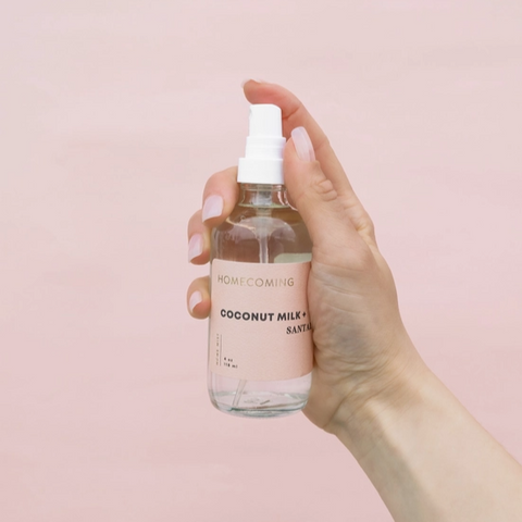 Hand holding a bottle of coconut milk with a pink background