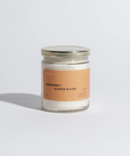 Candle in a glass jar with a label on a light gray background