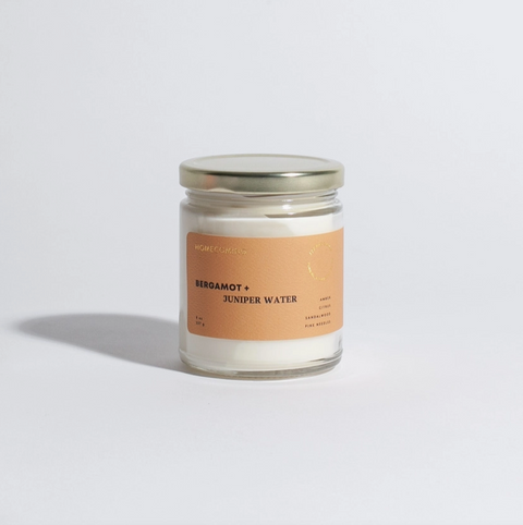 Candle in a glass jar with a label on a light gray background
