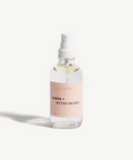 Clear spray bottle with a pink label on a white background