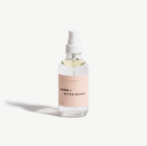 Clear spray bottle with a pink label on a white background