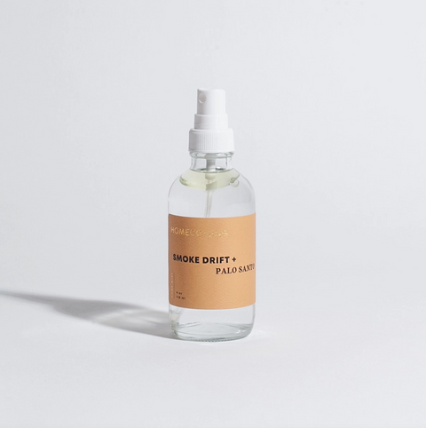 Clear spray bottle with a brown label on a light gray background