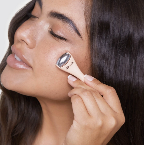Woman applying a cosmetic product to her face with a brush