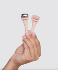 Hand holding two small skincare devices with 'skin' branding against a light background