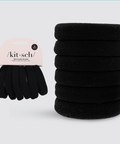 Stack of black hair elastics with a pink packaging label on a light blue background