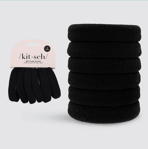 Stack of black hair elastics with a pink packaging label on a light blue background
