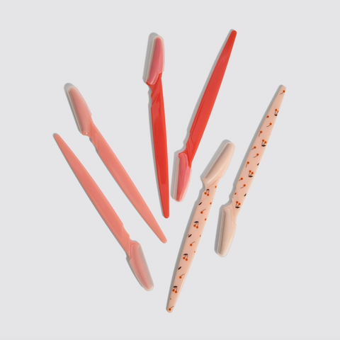 Set of pink and red makeup brushes on a light gray background