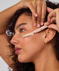 Woman having eyebrow threading performed by another person.