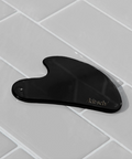 Black gourd-shaped tool with 'kitschy' branding on a gray tiled surface