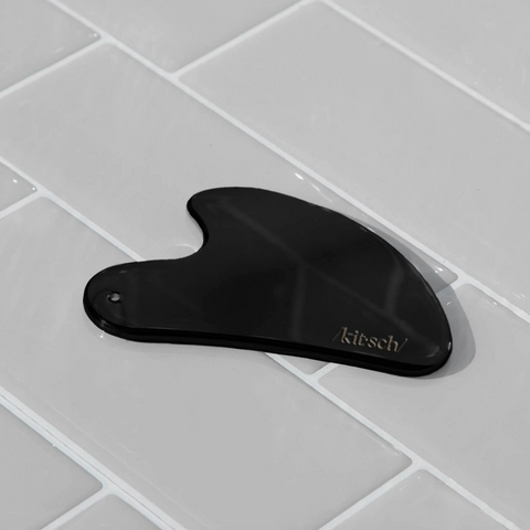 Black gourd-shaped tool with 'kitschy' branding on a gray tiled surface