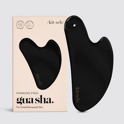 Black gua sha tool with packaging on a light gray background