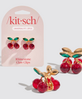 Cherry-themed rhinestone claw clips with 'kitsch' packaging on a light gray background