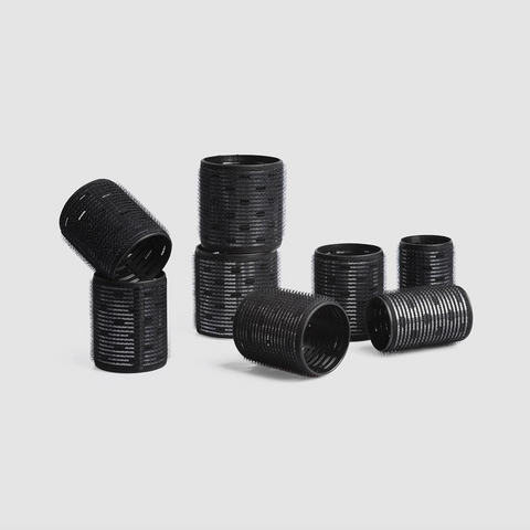 Set of black hair curlers on a light gray background