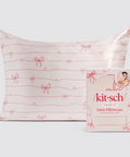Satin pillowcase with red bow pattern and 'kit-sch' packaging on a light gray background
