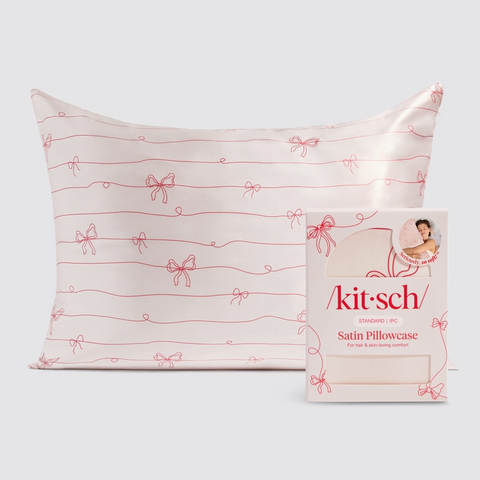 Satin pillowcase with red bow pattern and 'kit-sch' packaging on a light gray background