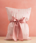 Decorative pillow with pink ribbon on a pink background