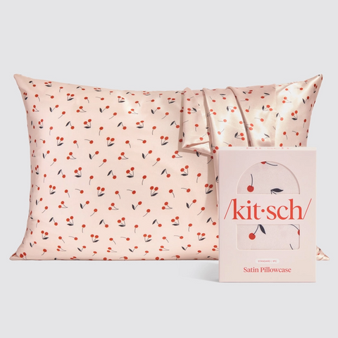 Satin pillowcase with cherry pattern and 'kit-sch' packaging on a light gray background