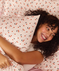 Woman lying on a bed with cherry-patterned bedding