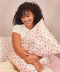 Woman holding a patterned pillow against a neutral background
