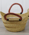 Woven basket with red handles on a wooden floor