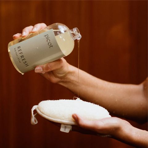 Person holding a bottle labeled 'picot' and a white pad against a brown background