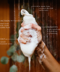 Hand holding a foamy bar of soap with showerhead and water droplets, labeled with product features.