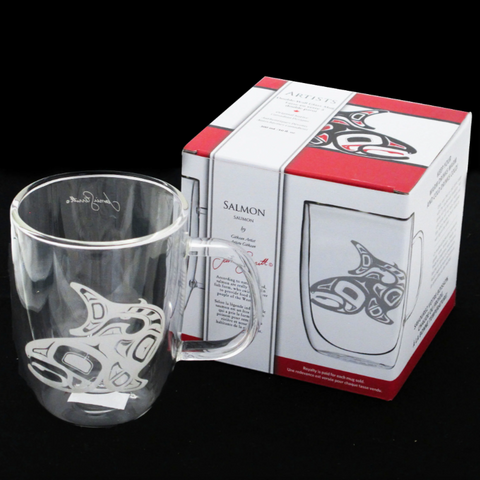 Clear glass mug with salmon design next to its packaging box on a black background