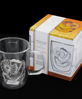 Clear glass mug with engraved design next to its packaging box on a black background