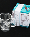 Clear mug with bird design and packaging on a black background